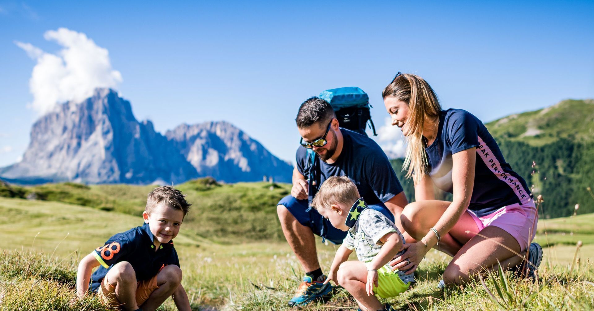 A family outdoors with a mountainous backdrop, likely in a natural setting.