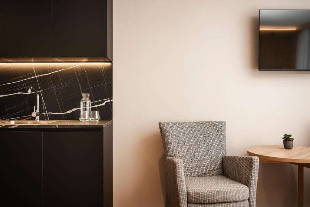 A modern kitchen with a marble backsplash, a built-in sink, and a wall-mounted TV.