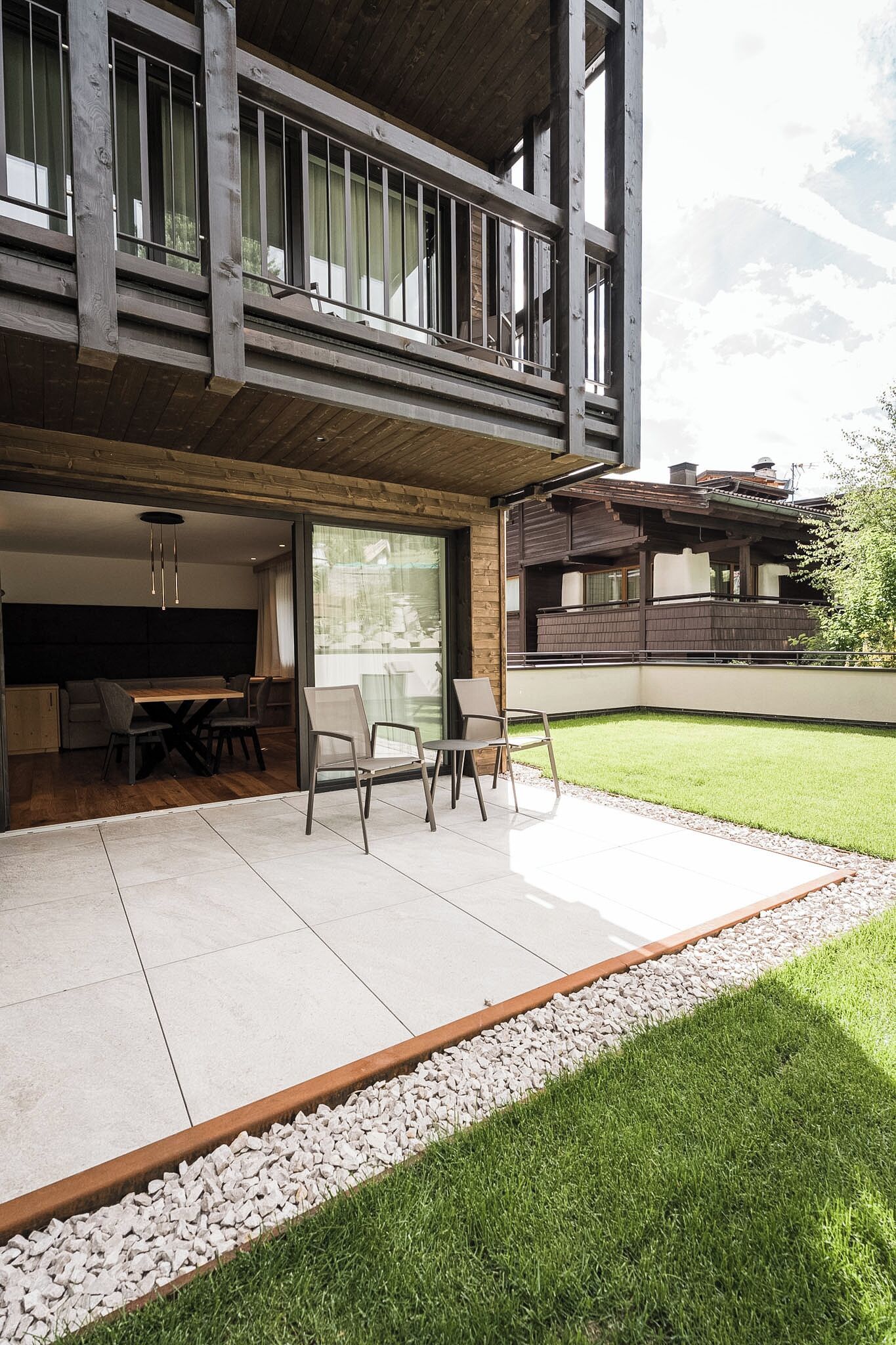 Een modern huis met een balkon, een eethoek en een verzorgd gazon.