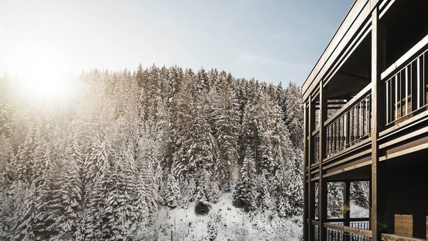 A building with a wooden balcony overlooking a snow-covered forest. - Hotel La Truga (Selva di Val Gardena)