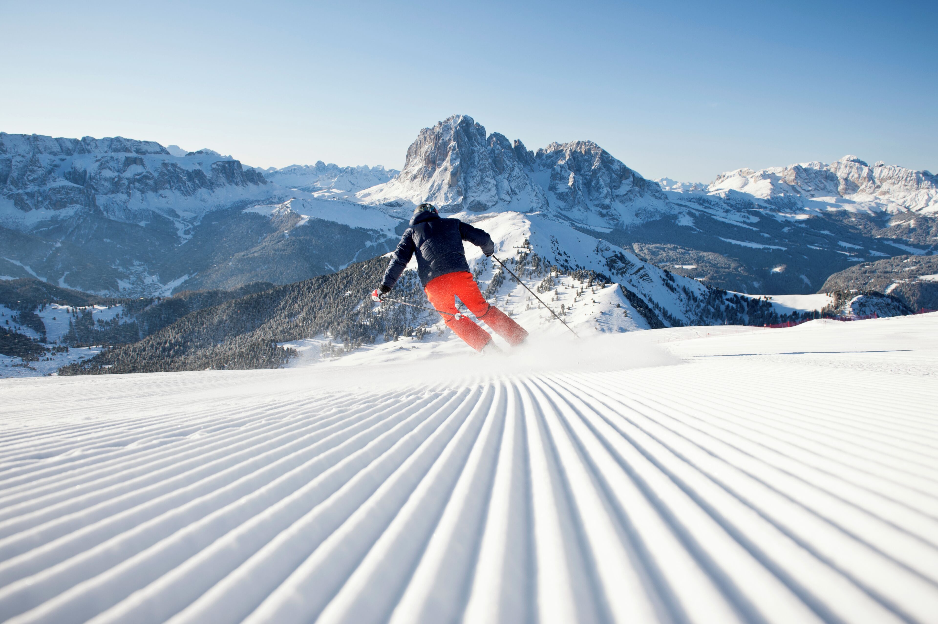 Un skieur sur une pente enneigée, avec une chaîne de montagnes en arrière-plan.