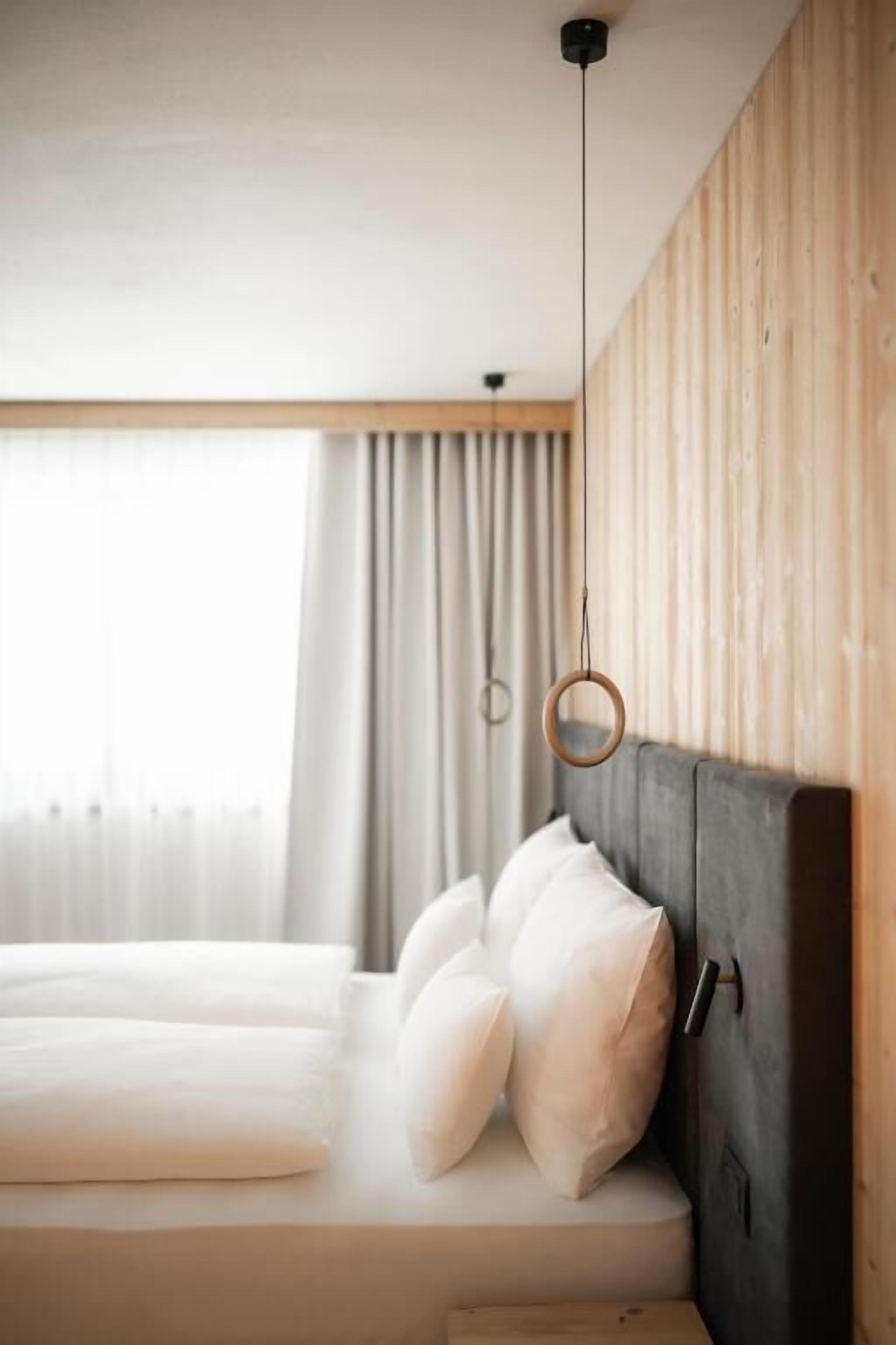 Quarto moderno com cama, painéis de madeira e luminária pendente.