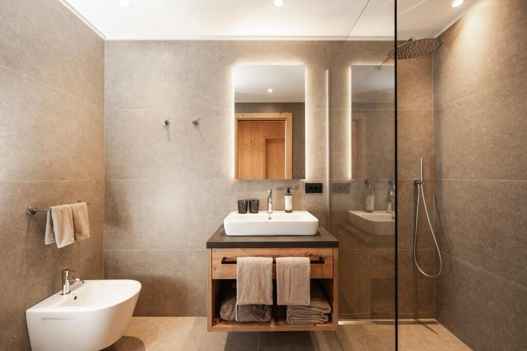 Un baño moderno con una bañera independiente, un tocador con espejo y una zona de ducha con paredes de vidrio.