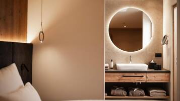 Un baño moderno con un espejo redondo, un lavamanos y un mueble de tocador de madera.