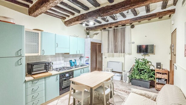 A compact kitchen with a dining area, a sofa, and a TV. - Appartamento vicino al Duomo (Siena)