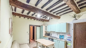 A compact kitchen with a dining area, a sofa, and a door leading to another room. - Appartamento vicino al Duomo (Siena)