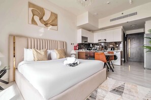 A modern hotel room with a large bed, a dining area, and a kitchenette. - Free Housekeeping Visits During Your Stay - Stayshort - Cozy Studio in Arjan That Sleeps 2 (Dubai)