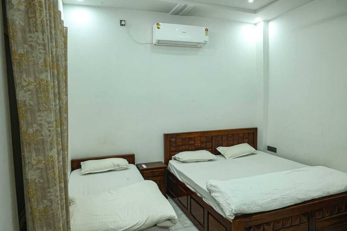 A room with two wooden beds, a white air conditioner, and a curtain on the left.