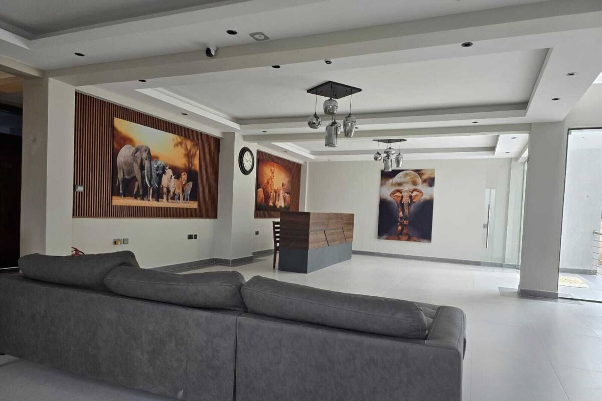 Una sala de estar moderna con un sofá gris, un mueble de madera y tres obras de arte colgadas en la pared que representan fauna silvestre.