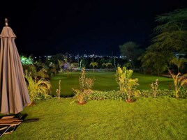 Vista nocturna de un campo de golf bien iluminado, con una carpa y sillas al frente.