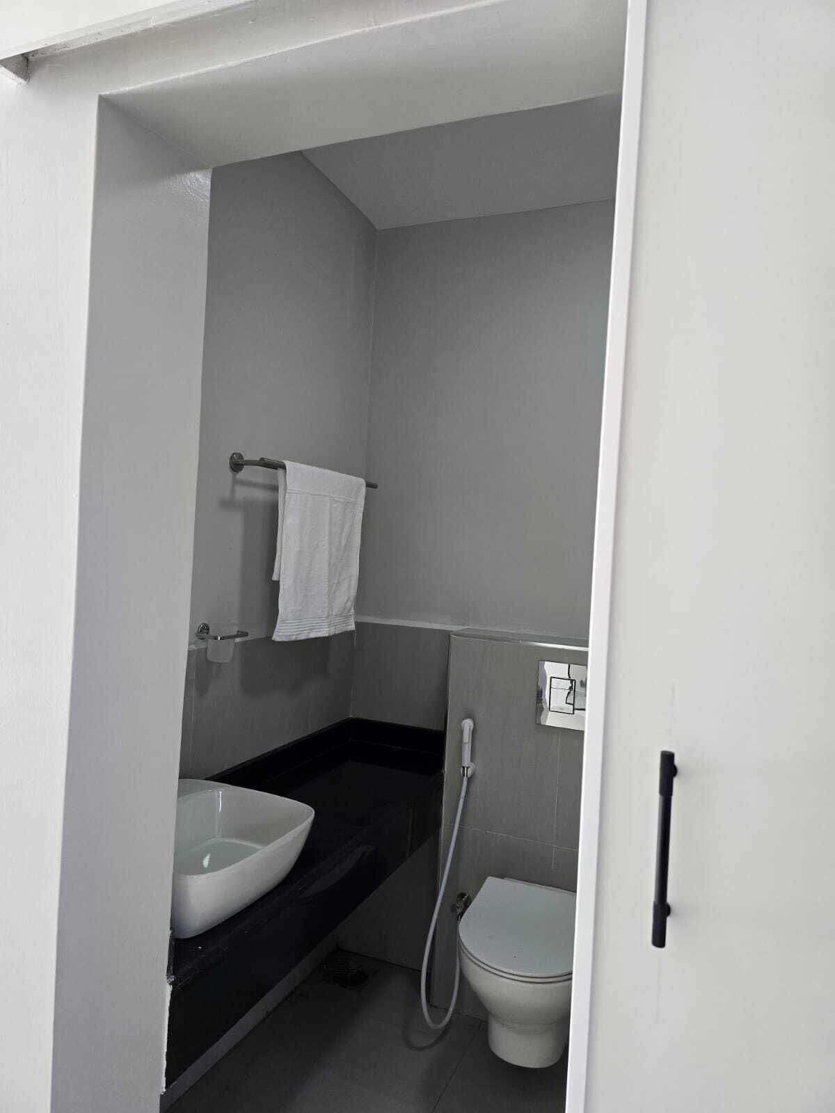 A small bathroom with a white sink, a toilet, and a shower.