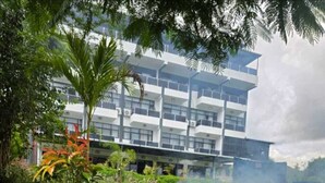 An outdoor barbecue with foil-wrapped meats, a grassy area, and a modern building in the background. - OLOISIRI NAMANGA HOTEL (Namanga)