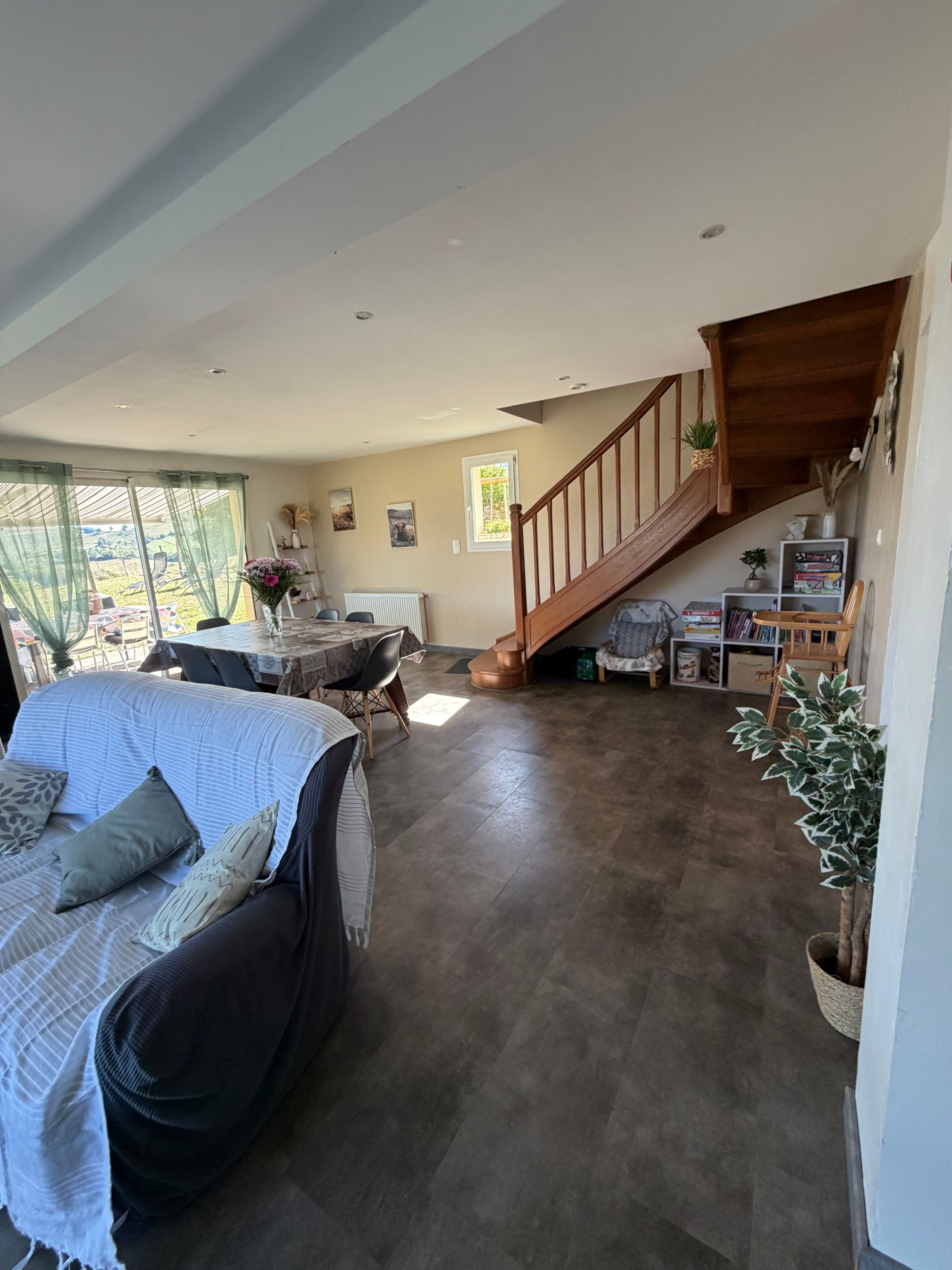A spacious living area with a sofa, a dining table, and a staircase leading to an upper level.