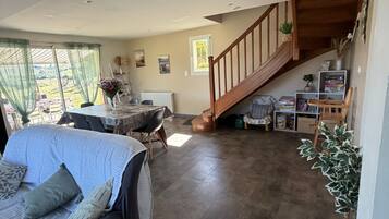 A spacious living area with a sofa, a dining table, and a staircase leading to an upper level.
