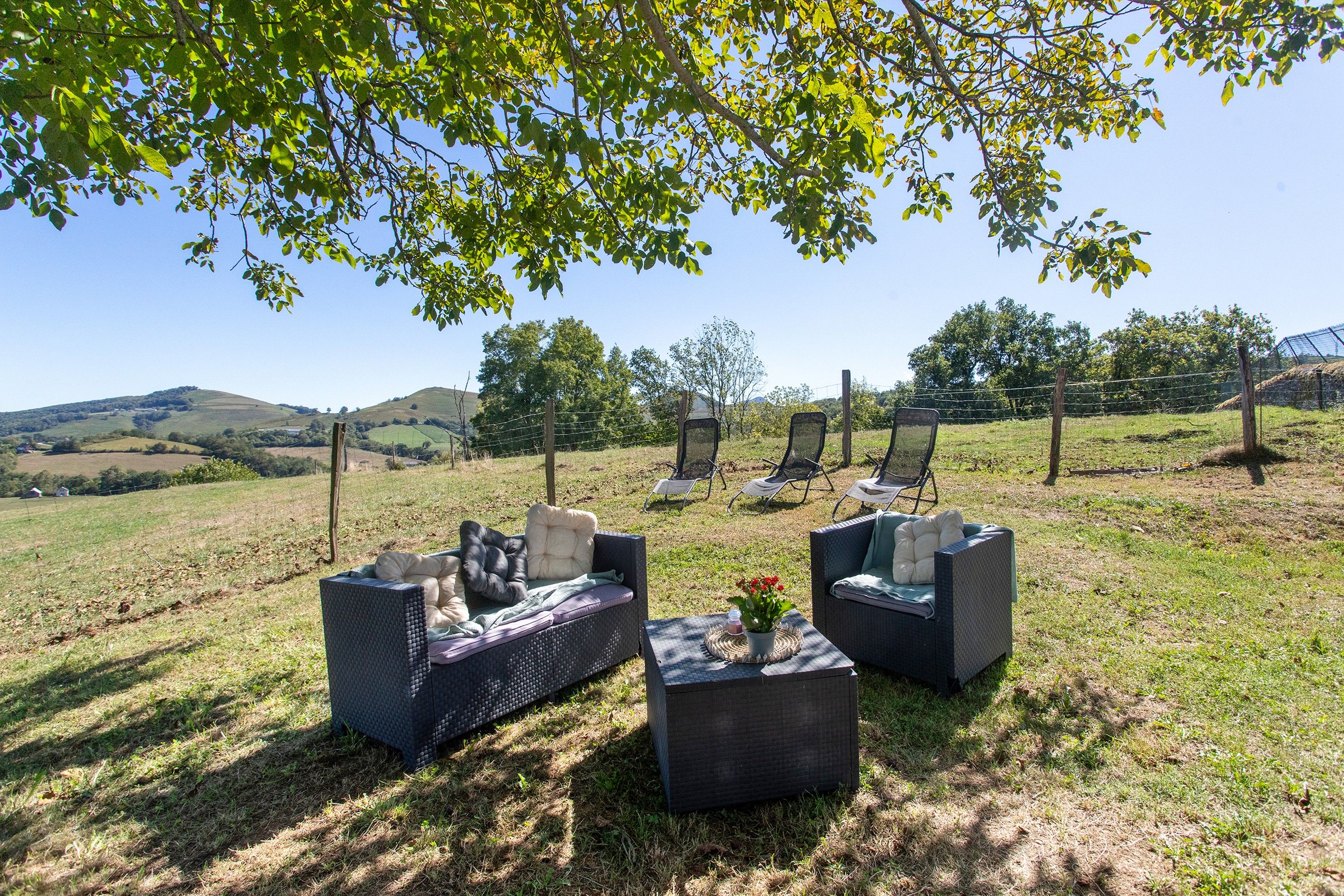 An outdoor seating area with wicker furniture and a view of rolling hills.