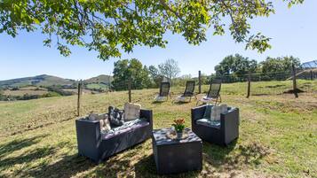 An outdoor seating area with wicker furniture and a view of rolling hills.