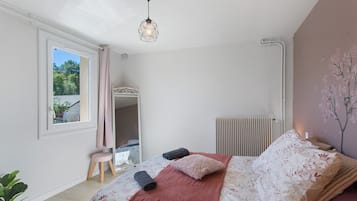 A bedroom with a bed, a radiator, a window, and a plant.