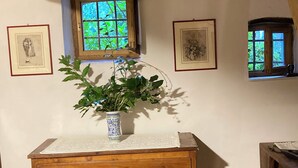 Un aparador de madera con cajones, un florero con una planta y cuadros en la pared.