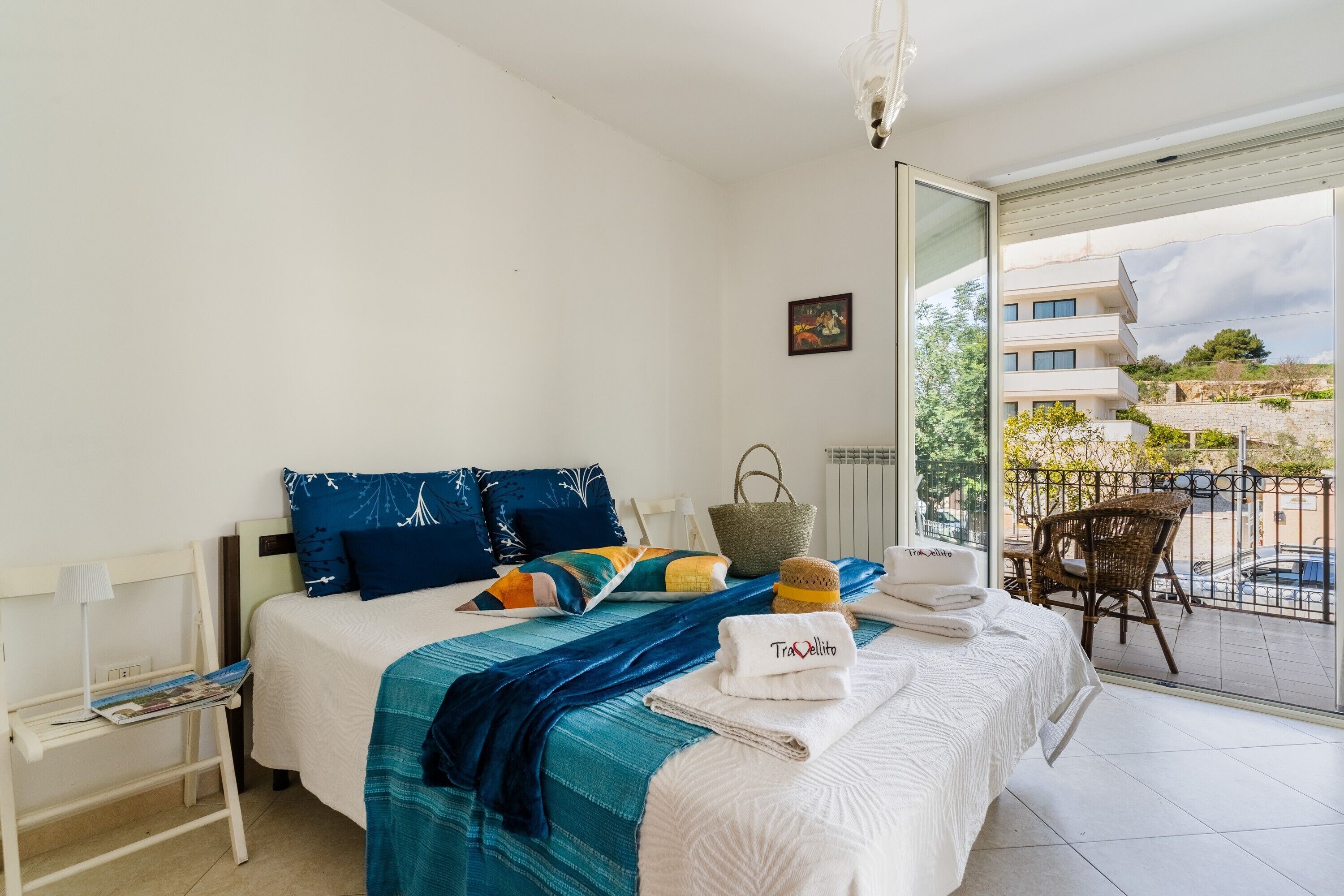 A hotel room with a bed, a chair, a table, and a balcony with a view.