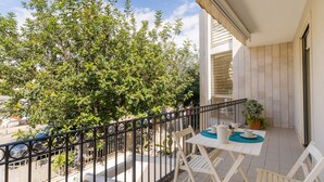 A balcony with a table and chairs, a potted plant, and a view of a tree and parked car. - Holiday Home 'Casa Dafne in Otranto 6 Guests' with Balcony, Wi-Fi and Air Conditioning (Otranto)