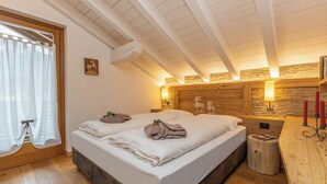 Un dormitorio con techo de madera, una cama con toallas, un taburete pequeño y una pared de madera con diseño de piedra.