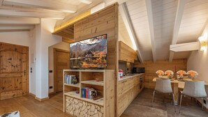 Un interior de madera con televisor, estanterías, una zona de comedor y una pared de piedra.
