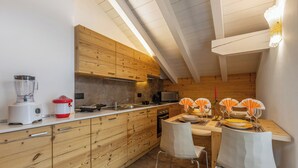 Una cocina moderna con armarios de madera, una mesa de comedor con sillas y un horno empotrado.