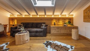 Una habitación estilo loft con tragaluces, vigas de madera, un sofá de cuero, una mesa de centro de madera y un tapiz de cuero de vaca.