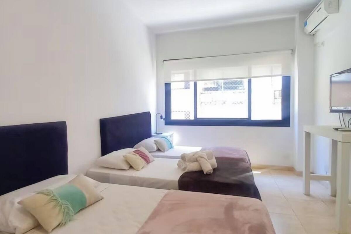 Una habitación de hotel con dos camas, un escritorio y una ventana con persianas.