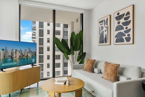 A modern living room with a television, sofa, coffee table, and artwork. - FIFA Fan Fest at Bayfront  | Modern 2BR | Gym (Miami)