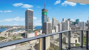 Un edificio alto con vistas a un paisaje urbano, que incluye varios rascacielos y una masa de agua.
