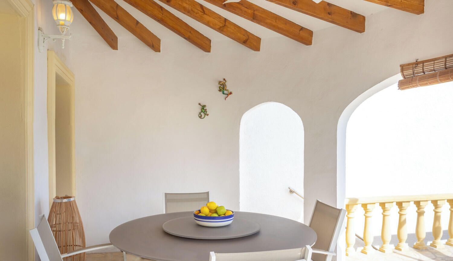Una mesa redonda con un frutero, una silla y una lámpara.