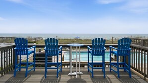 Une terrasse avec une piscine, des chaises bleues et une vue sur l’océan.