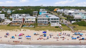 Une ville côtière dotée de propriétés en bord de mer, d’une promenade en bord de plage et d’une plage avec des parasols et des gens.