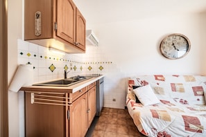 A compact kitchen with wooden cabinets, a sink, and a wall-mounted clock. - Apartment 'Entre Lac et Montagne' with Lake View and Balcony (Thollon-les-Mémises)