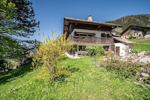 A two-story chalet with a balcony, surrounded by lush greenery and a mountain backdrop. - Apartment "Le Léman" with Mountain View and Wi-Fi (Vacheresse)