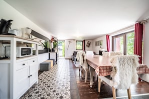 A kitchen with a microwave, cabinets, and a dining area with a table and chairs.