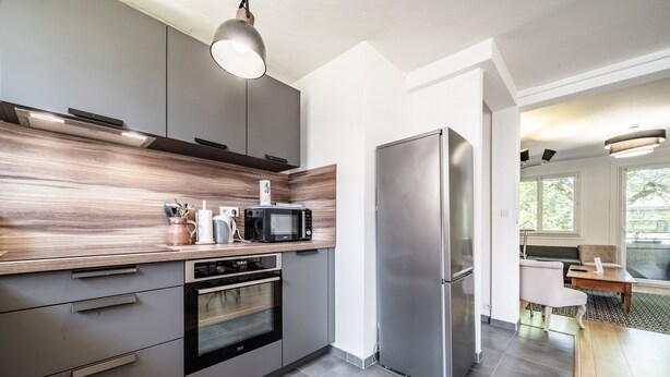 Een moderne keuken met inbouwapparatuur, grijze kastjes en een houten aanrechtblad.