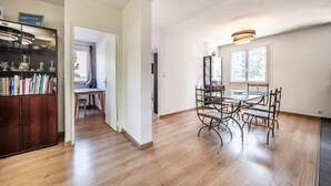 Een ruime kamer met een eettafel, stoelen en een kast vol boeken.