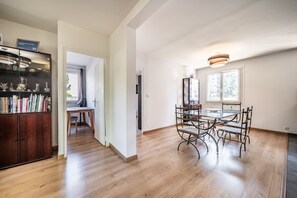 Habitación amplia con una mesa de comedor, sillas y un armario lleno de libros.