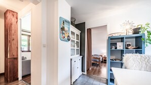 Un interior moderno con una puerta de madera, armarios blancos, una estantería azul y una mesa blanca.