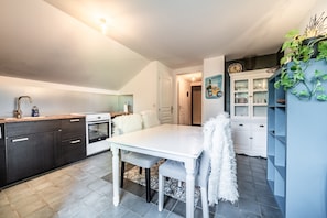A modern kitchen with dark cabinets, a white table, and a blue cabinet with decorative plants. - Apartment "Les Cornettes": Panoramic Mountain Views (Vacheresse)