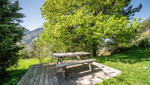 Una mesa de picnic en un área con césped, árboles y montañas al fondo.