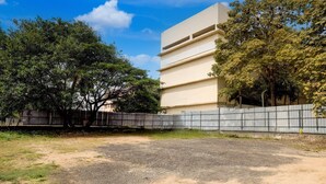 Een gebouw met een plat dak, een betonnen muur en een verhard gebied ervoor.