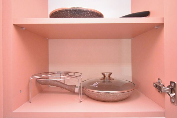 A pink cabinet with a glass stove top and a pot on top.