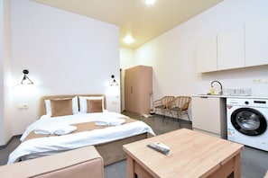 Une chambre d’hôtel équipée d’un lit, d’une petite table, d’une chaise, d’un lave-linge et d’une kitchenette.