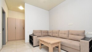 A minimalist living room with a beige sofa, a wooden coffee table, and a small side table. - Seva Apart-Hotel (Yerevan)