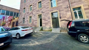 A multi-story building with a brick facade, several windows, and a visible entrance. There are parked cars in front. - Seva Apart-Hotel (Yerevan)