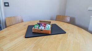 Une table ronde en bois surmontée d’un tapis noir, deux chaises en bois et une boîte contenant divers objets.