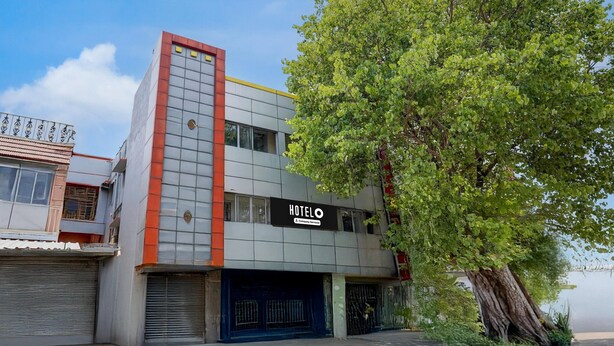 A modern building with a sign reading 'HOTEL' and a tree in front. - Deluxe BV Stayz (Chennai)